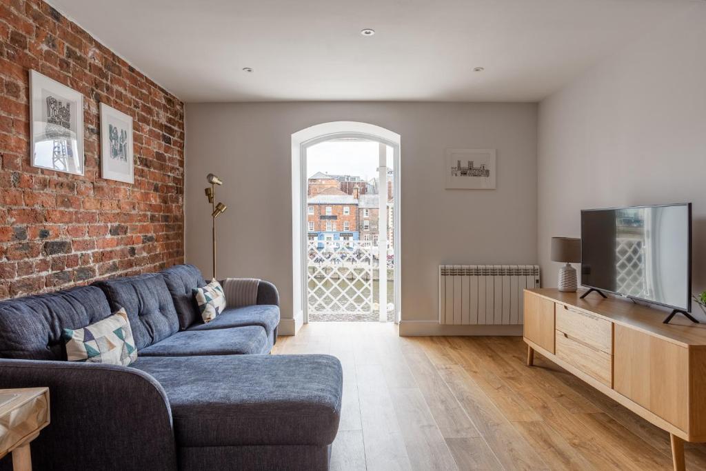 a living room with a blue couch and a brick wall at Luxury Apartment Woodsmill View - on the river - with balcony - Recently refurbished in York