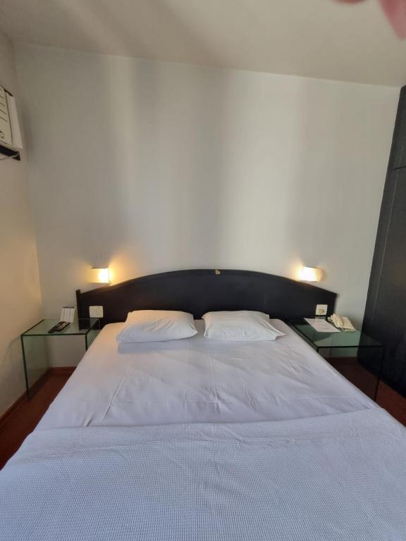 1 cama blanca grande con 2 mesitas de noche al lado en Condomínio Max Savassi Superior apto 1302, en Belo Horizonte