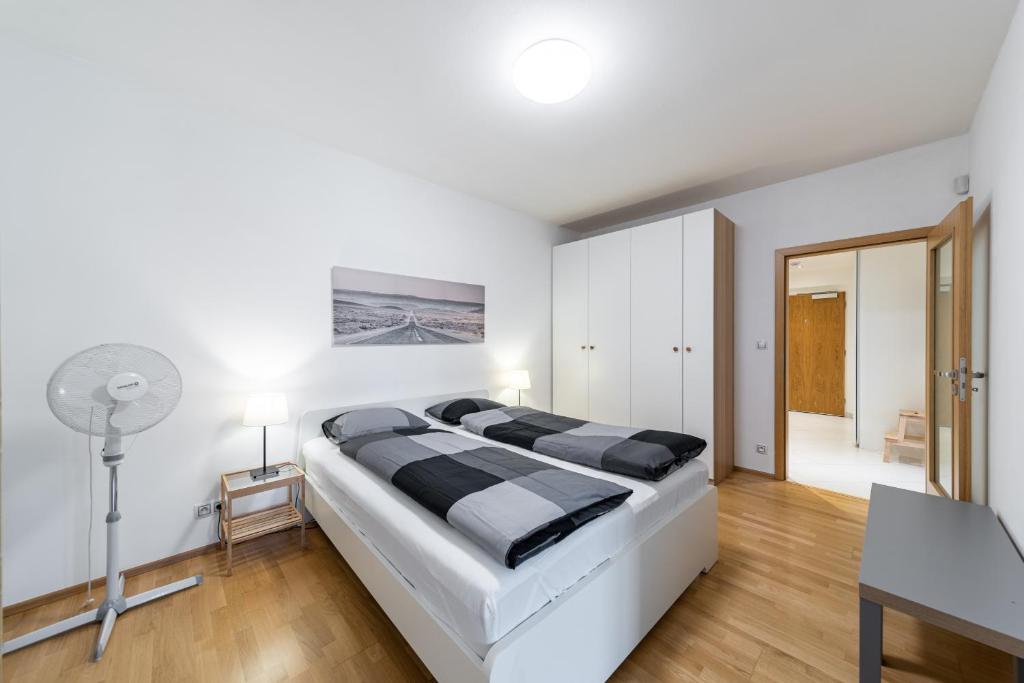 a white bedroom with a large bed and a desk at Garden Towers Apartments in Prague