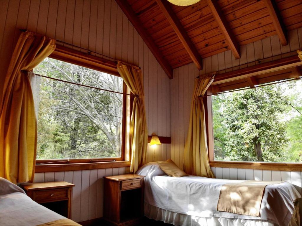 two beds in a room with two windows at Apart Hotel del Pellin in San Martín de los Andes