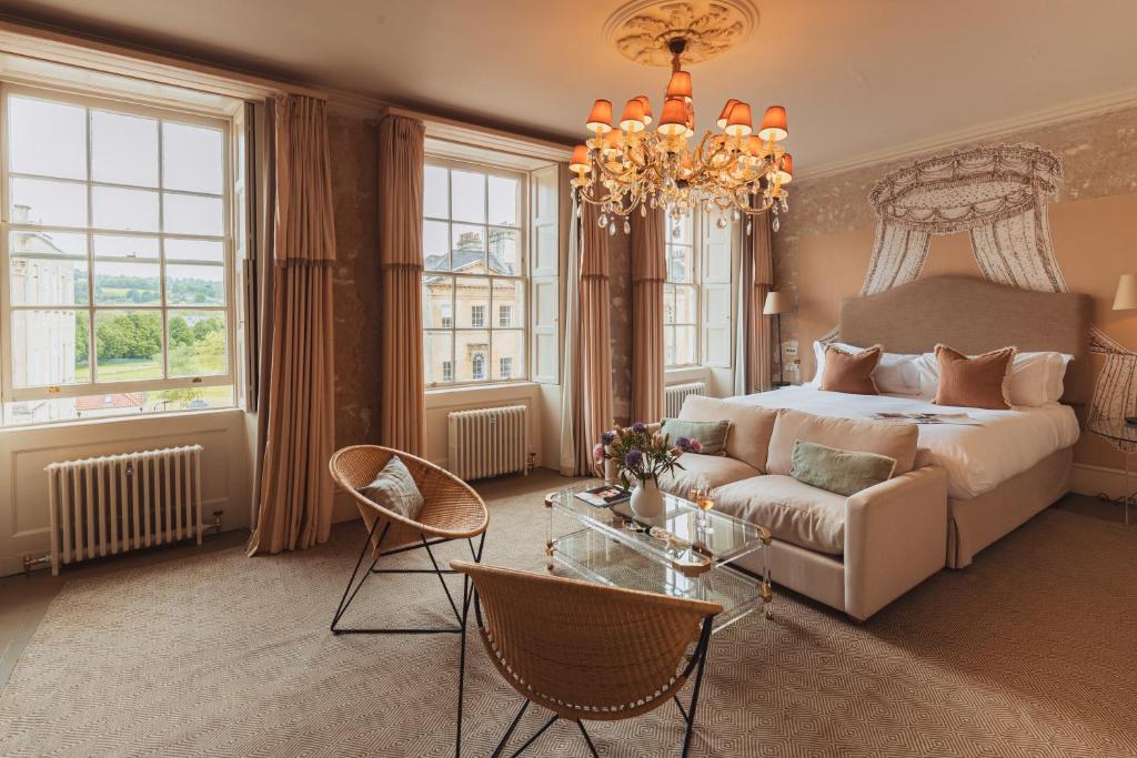 a bedroom with a bed and a couch and a chandelier at No 15 by GuestHouse, Bath in Bath