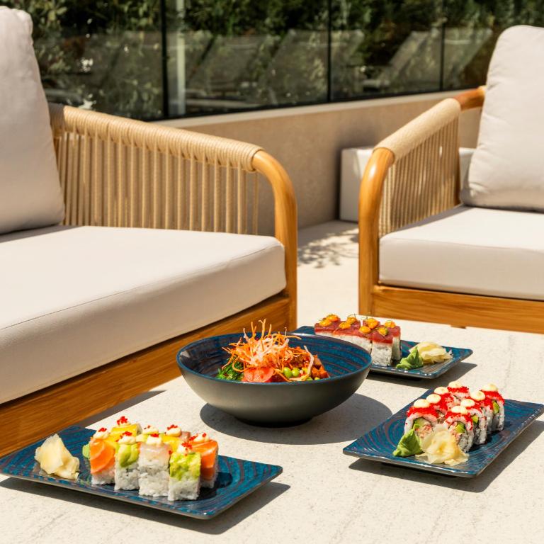 three plates of food sitting on a table with chairs at The Londoner Hotel St. Julian's in St. Julianʼs