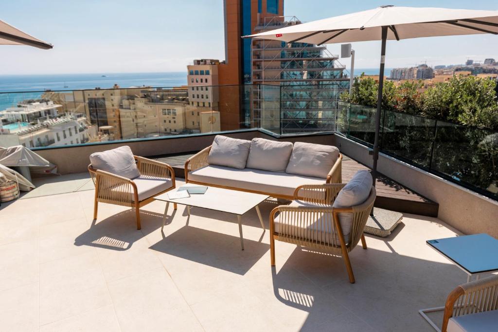 balcón con mesa, sillas y sombrilla en The Londoner Hotel St. Julian&#39;s, en San Julián