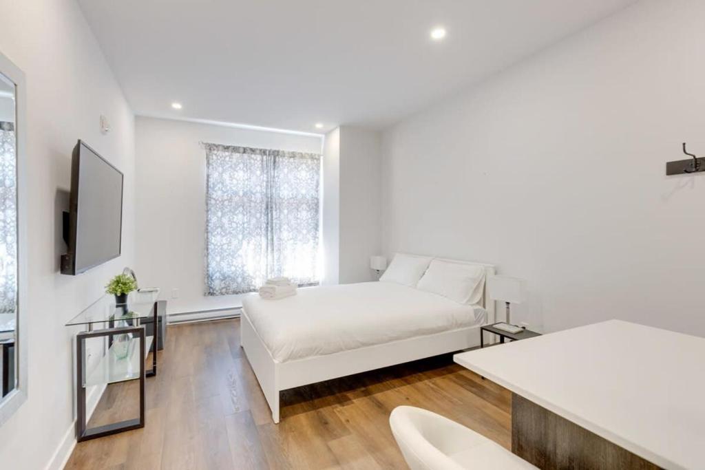 a white bedroom with a bed and a window at M11 Upscale Studio wQueen Bed AC Prime Location in Montréal
