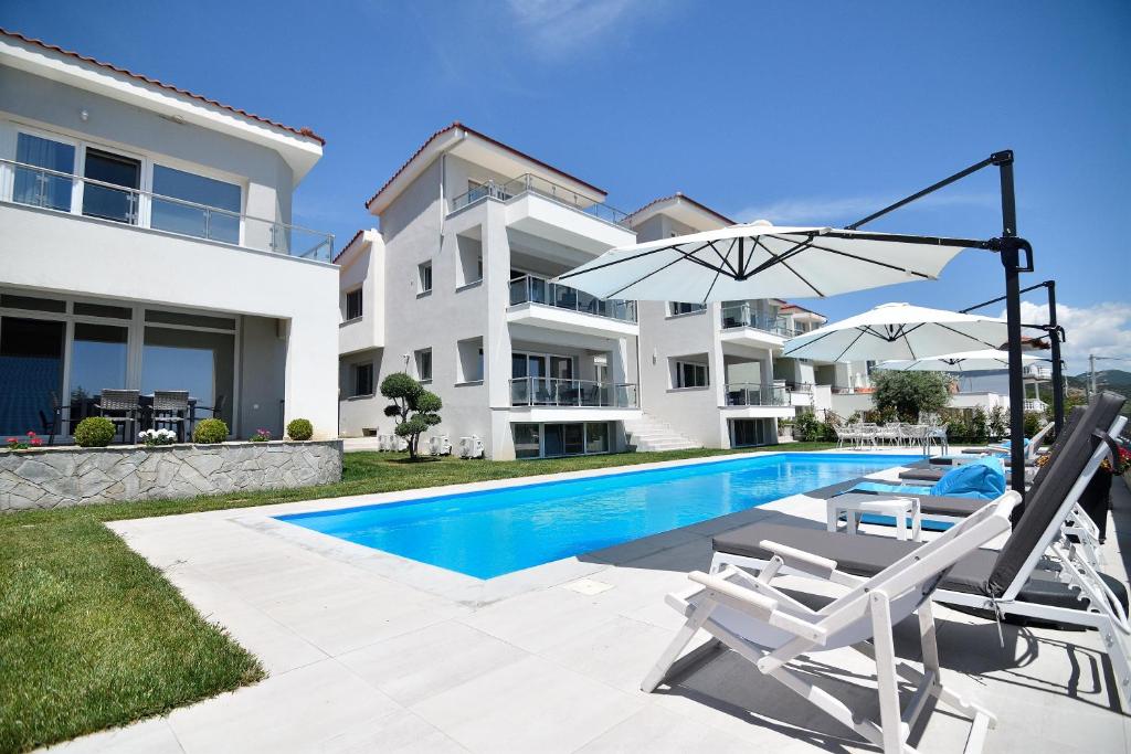 a villa with a swimming pool and two chairs and an umbrella at Eleonas View Suites in Eleftheres