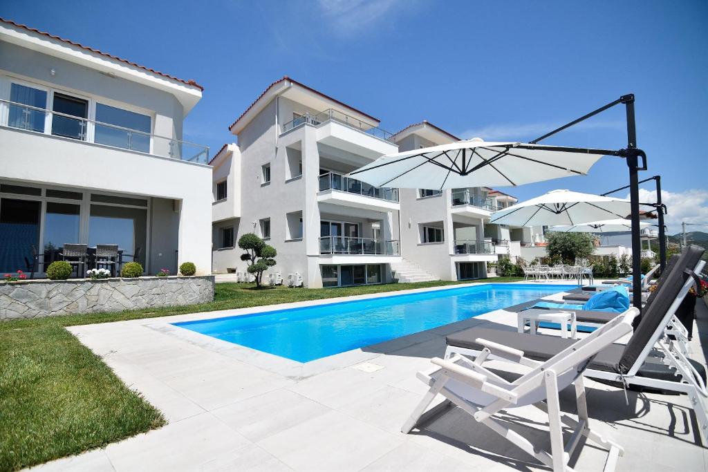 a villa with a swimming pool and two chairs and an umbrella at Eleonas View Suites in Nea Peramos