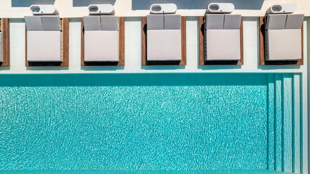 a row of chairs next to a swimming pool at The Londoner Hotel St. Julian's in St. Julianʼs