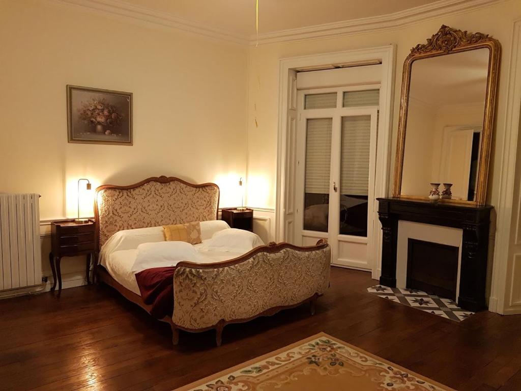 1 dormitorio con cama, espejo y chimenea en Tradition Plombières en Plombières-les-Bains