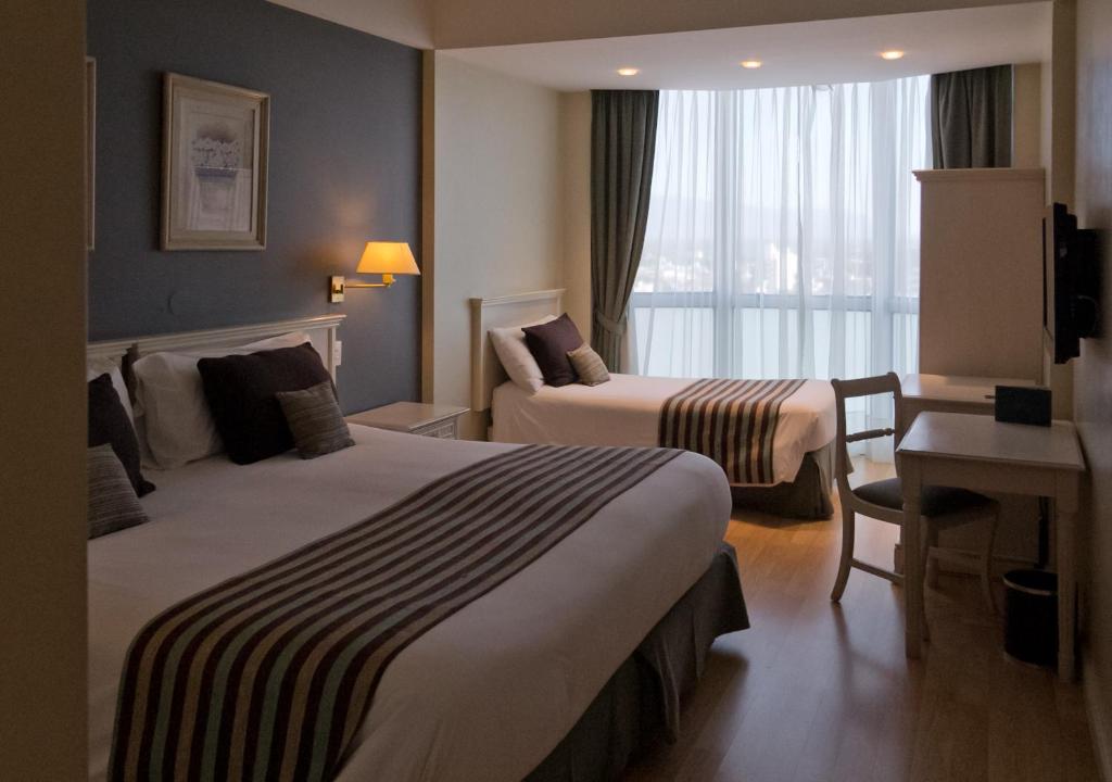 um quarto de hotel com duas camas e uma secretária e uma janela em Amérian Catamarca Park Hotel em San Fernando del Valle de Catamarca