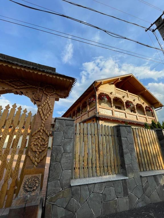 a building with a wooden fence in front at Pensiunea Valea Muntelui in Bîrsana