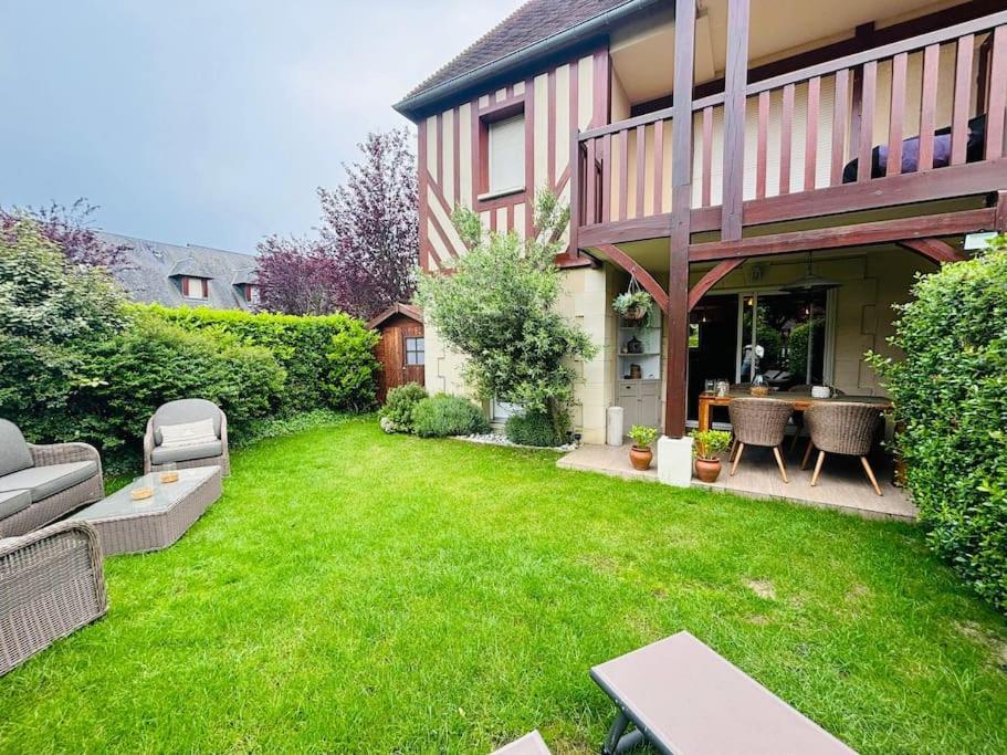 une arrière-cour avec une pelouse verdoyante et une maison dans l'établissement Le sublime Olivier Normand, 3P cosy et luxe avec jardin, piscine & tennis, vélos, à Deauville