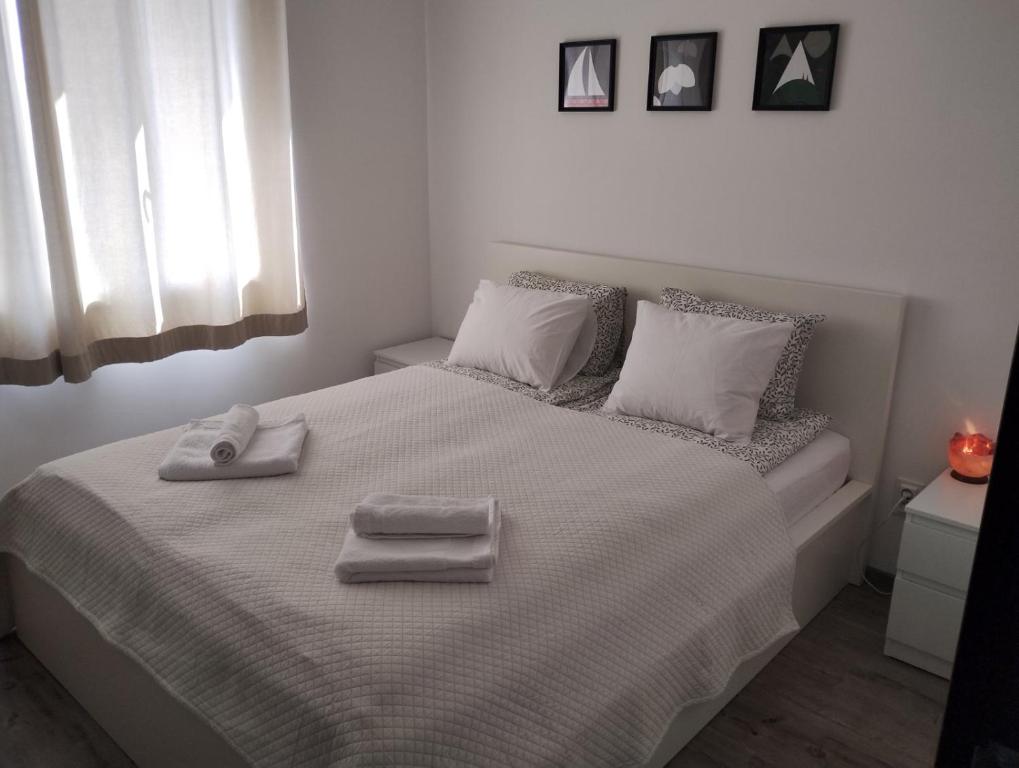 a white bedroom with a bed with two towels on it at Happy Apartment & Free Breakfast - Mladost in Sofia
