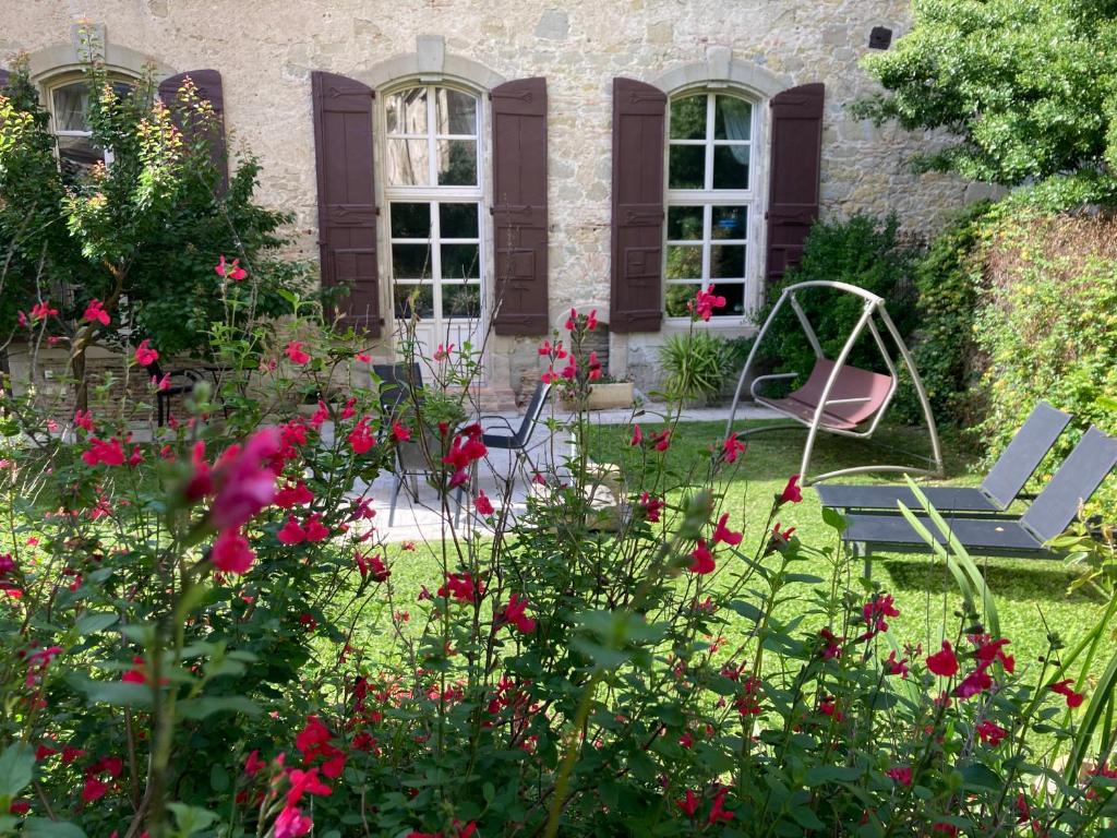 einen Garten mit Blumen und Stühlen vor einem Haus in der Unterkunft Les Ordalies in Castelnaudary