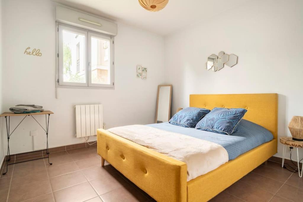 a bedroom with a yellow bed with blue pillows at Appartement avec Jardin et Terrasse près de Paris in Mantes-la-Jolie