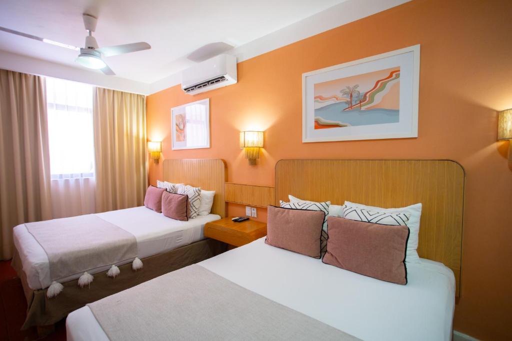 プエルト・バジャルタにあるHotel Tropicus Boutiqueのオレンジ色の壁のホテルルーム内のベッド2台