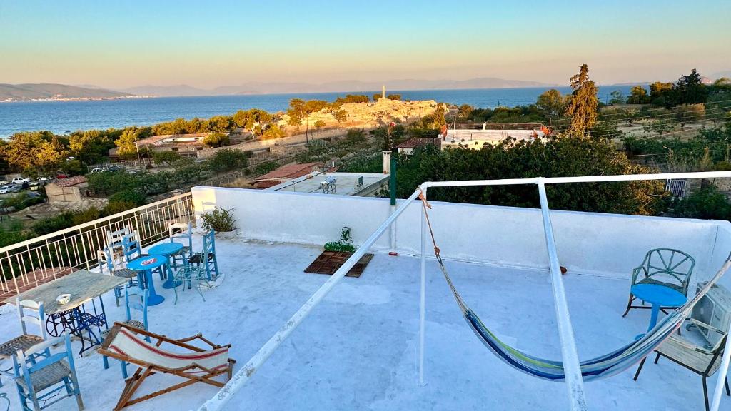un balcon avec une balançoire, des tables et des chaises dans l'établissement Appartement vue sur mer SOUL FAMILY, Egine, à Égine