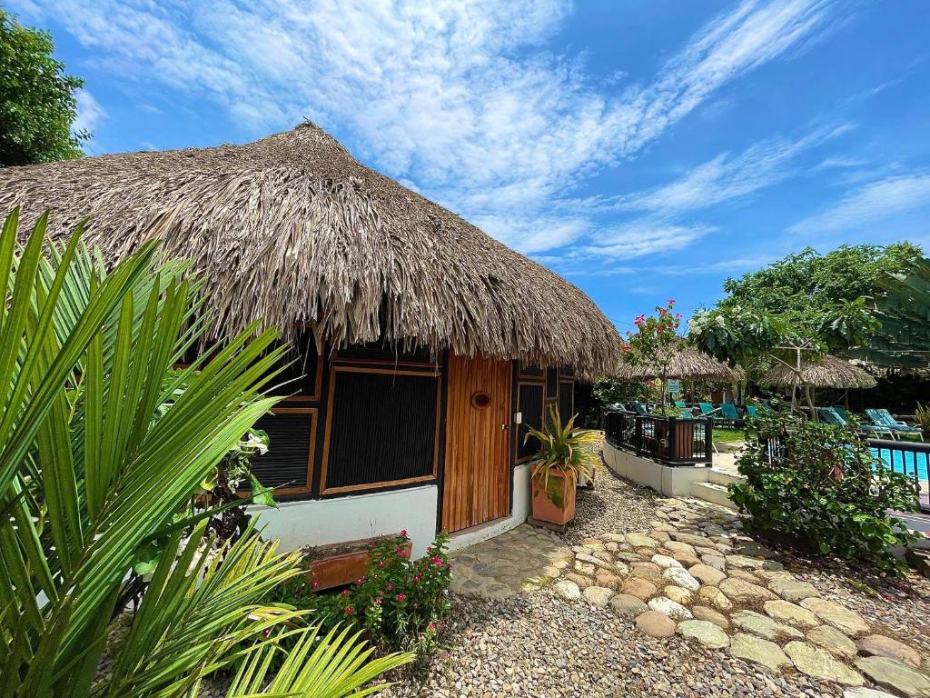 una casa con techo de paja y piscina en Bikini Hotel & Pool, en Palomino