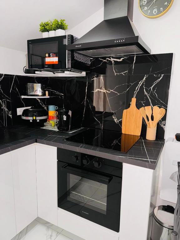 - une cuisine noire et blanche avec cuisinière dans l'établissement Appartement Royale 2 Pièces de 35 m2, à Noisy-le-Sec