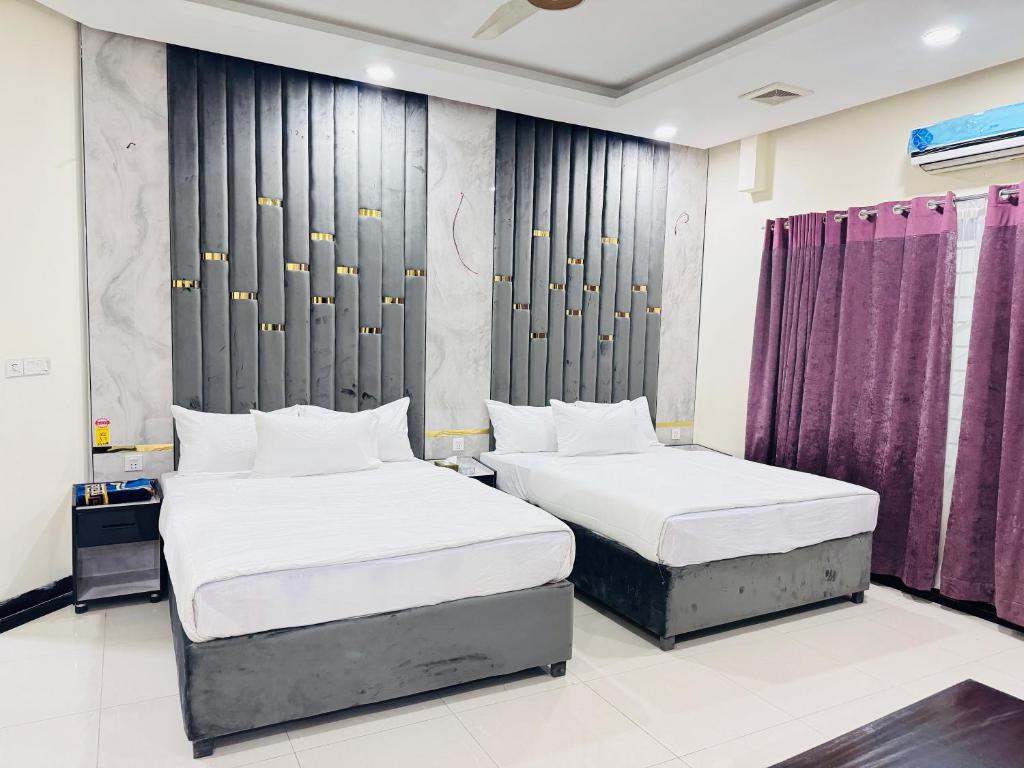 2 camas en una habitación con cortinas moradas en Rose Valet Guest House, en Islamabad