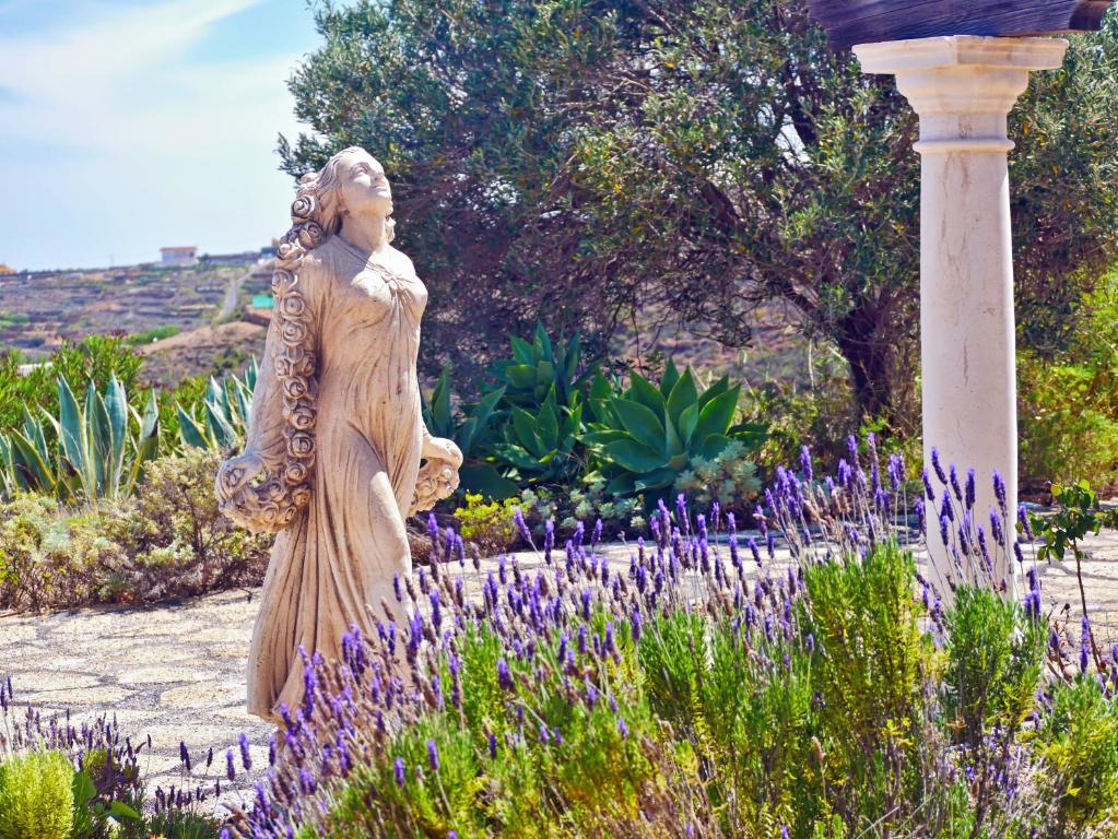 una estatua de una mujer en un jardín con flores púrpuras en Casa Rosa, Arico Viejo La Sabinita - baden, wandern, klettern, Individualurlaub jenseits des Massentourismus,, en La Sabinita
