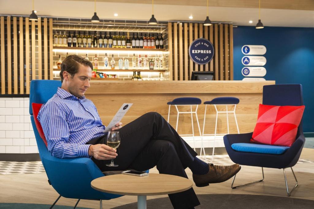 a man sitting in a chair with a glass of wine at Holiday Inn Express Ajaccio by IHG in Ajaccio