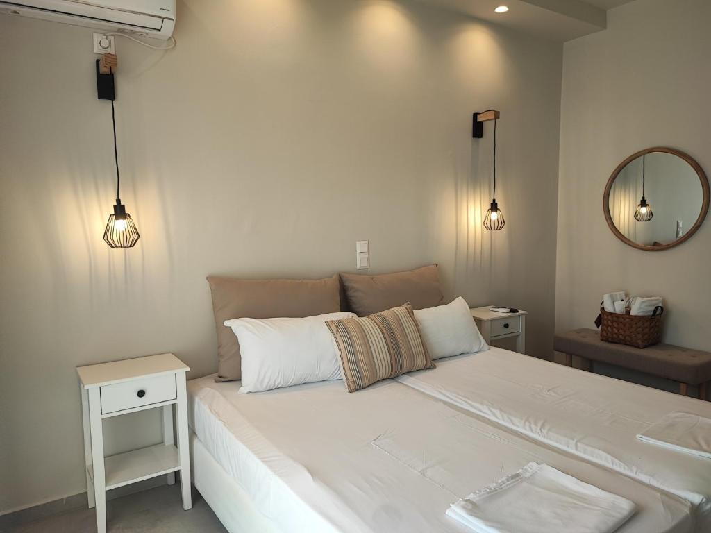 ein Schlafzimmer mit einem großen weißen Bett und einem Spiegel in der Unterkunft Akrogiali in Skala