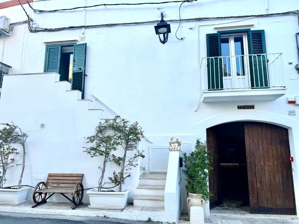 - un bâtiment blanc avec une porte en bois et un banc dans l'établissement DIMORA MOLINI, à Monopoli
