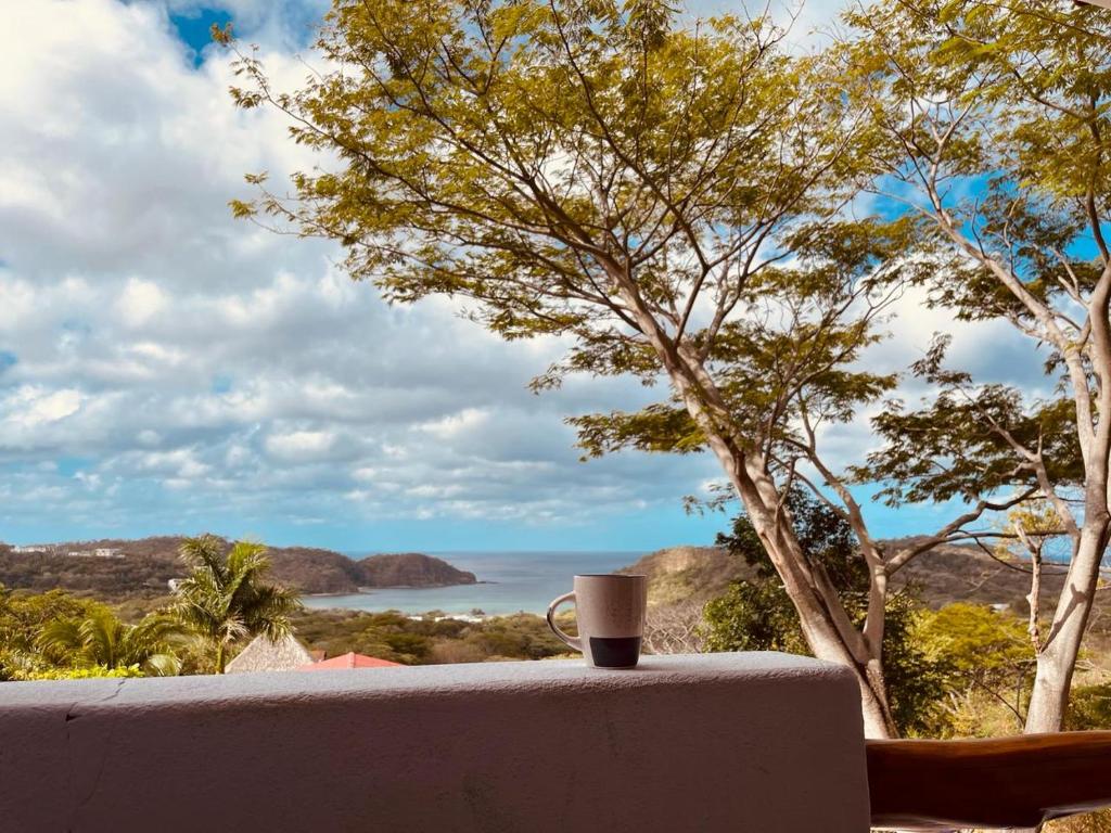 uma chávena de café sentada numa mesa com vista para o oceano em El Jardin em San Juan del Sur