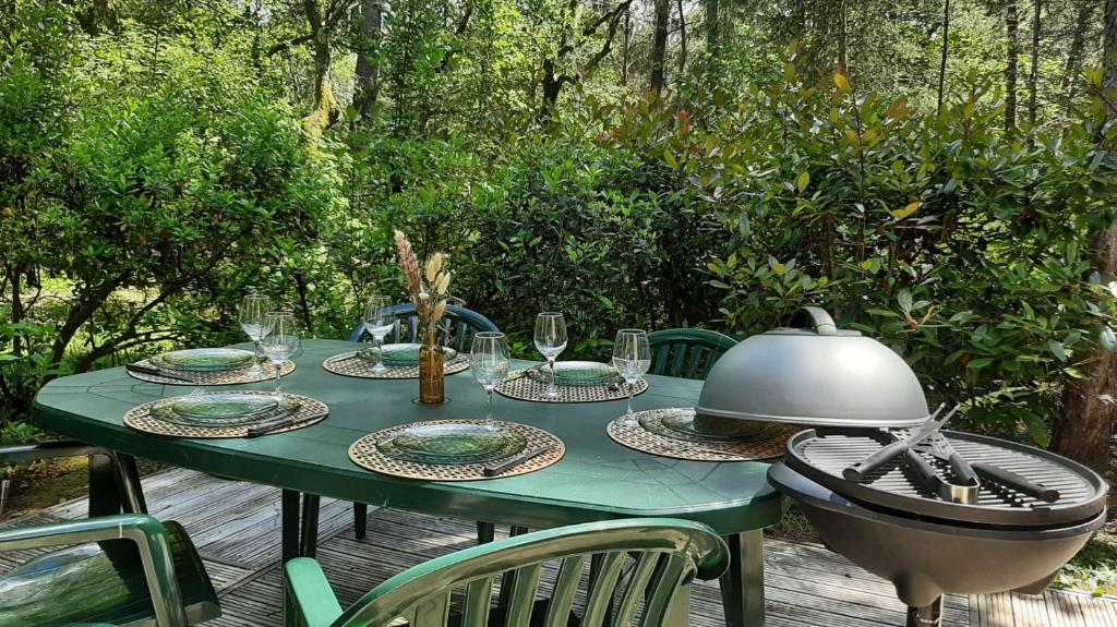 a green table with plates and glasses on it at Cottage-4p-Les Hauts de bruyère-293 in Chaumont-sur-Tharonne