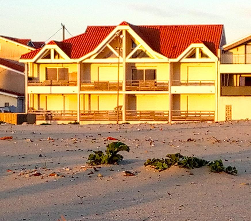 un grand bâtiment jaune avec un toit rouge dans l'établissement Au pied de la dune, à Biscarrosse