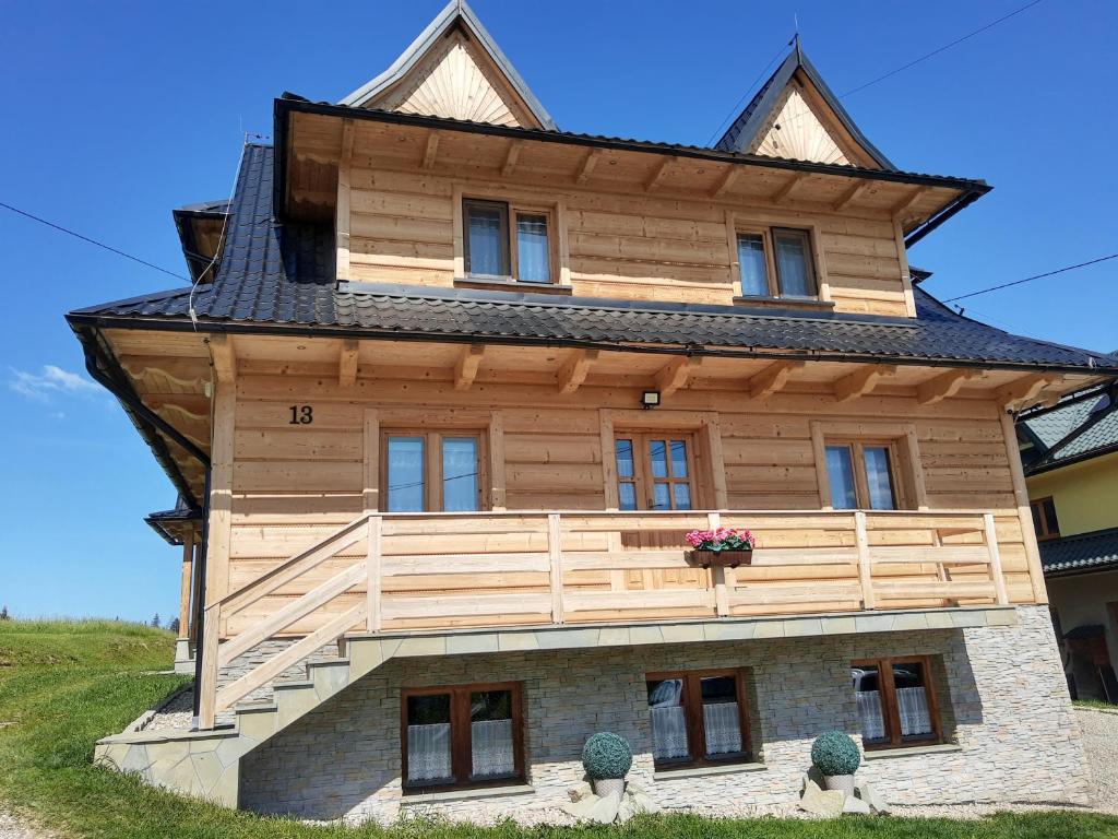 a wooden house with a gambrel roof at Pokoje Gościnne Iwona in Brzegi
