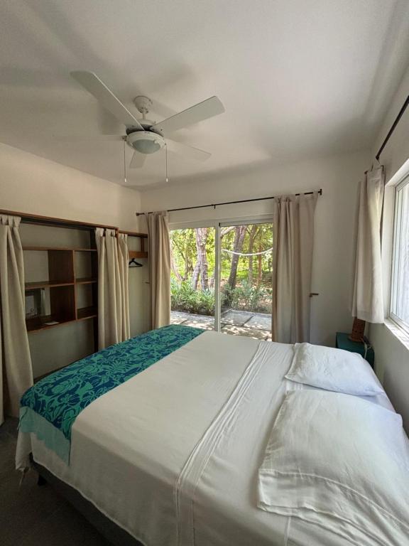 a bedroom with a bed with a ceiling fan and a window at Casa Mariposa in Tola