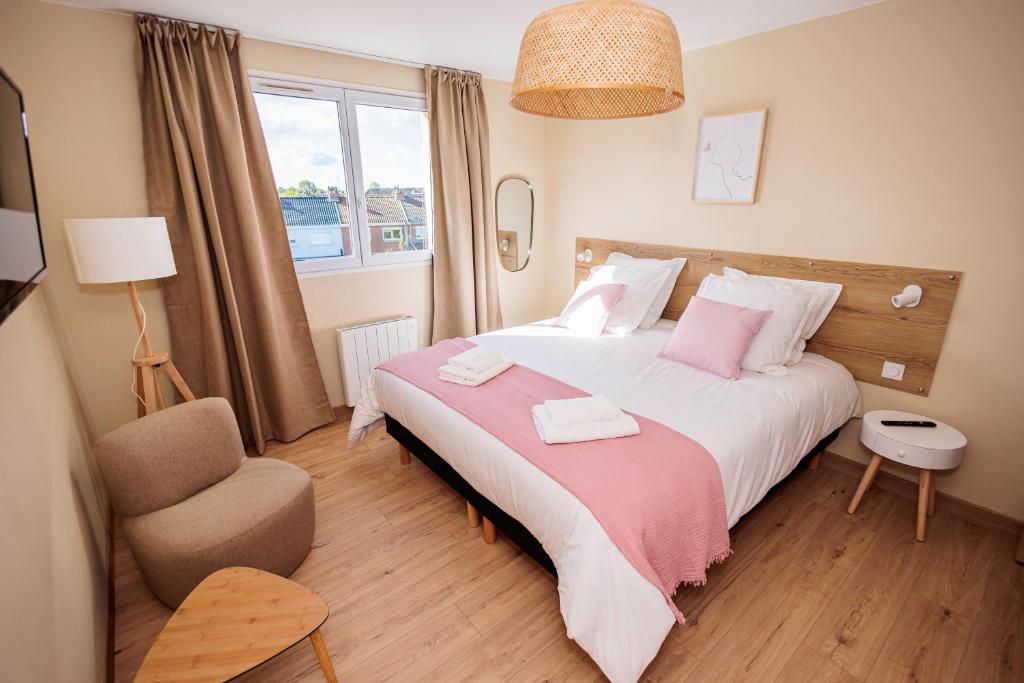 um quarto com uma cama grande e uma cadeira em Appartement 2 chambres et balnéo proximité Dunkerque em Dunkerque