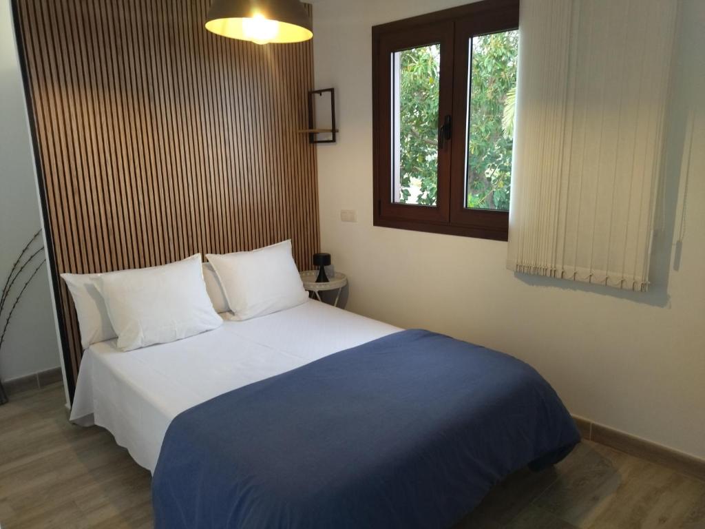 1 dormitorio con 1 cama con manta azul y ventana en 2Faros, en La Guancha