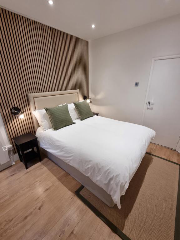 um quarto com uma grande cama branca e 2 almofadas verdes em Victoria Lodgings London em Londres