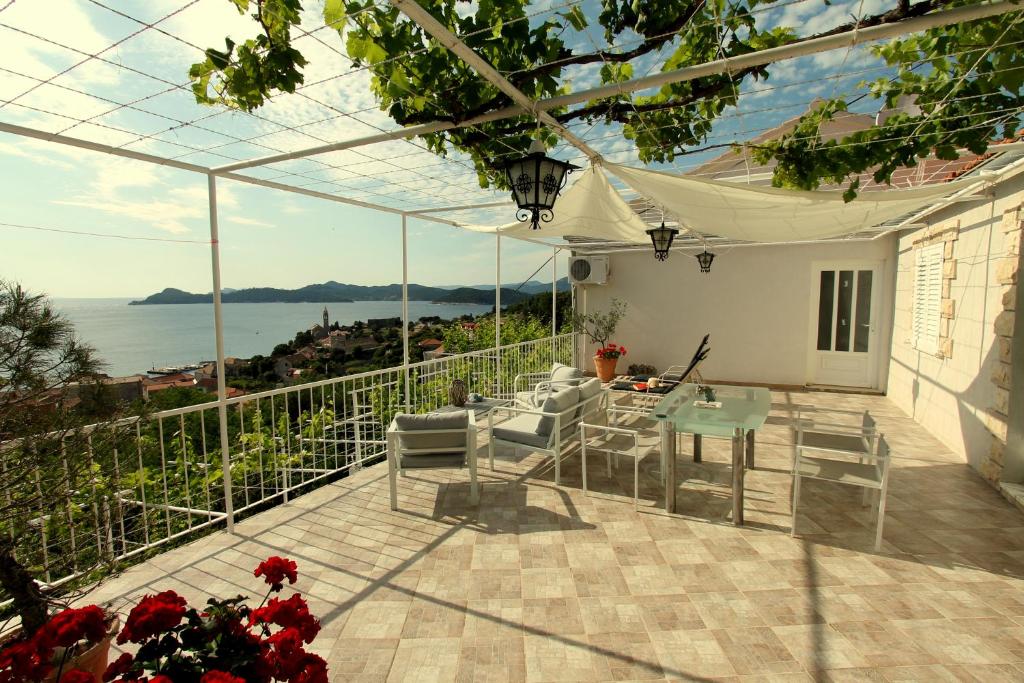 eine Terrasse mit einem Tisch, Stühlen und Meerblick in der Unterkunft Apartments Cervelin in Lopud Island