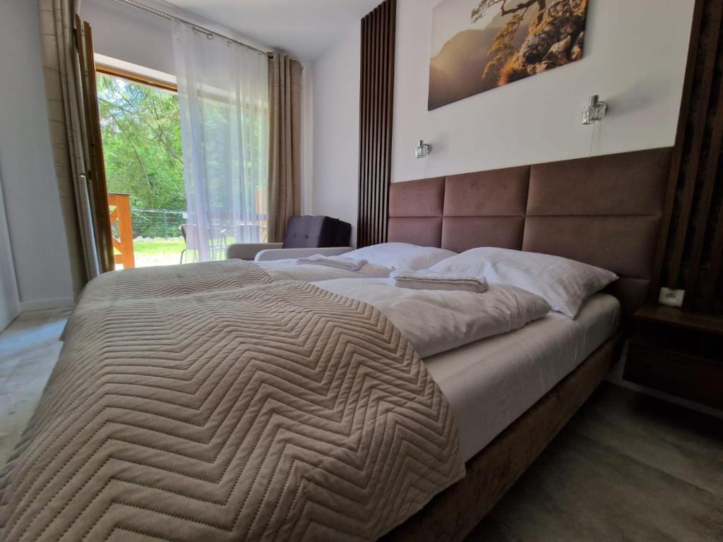 ein großes Bett in einem Schlafzimmer mit einem großen Fenster in der Unterkunft Apartament 10 z ogrodem in Szklarska Poręba