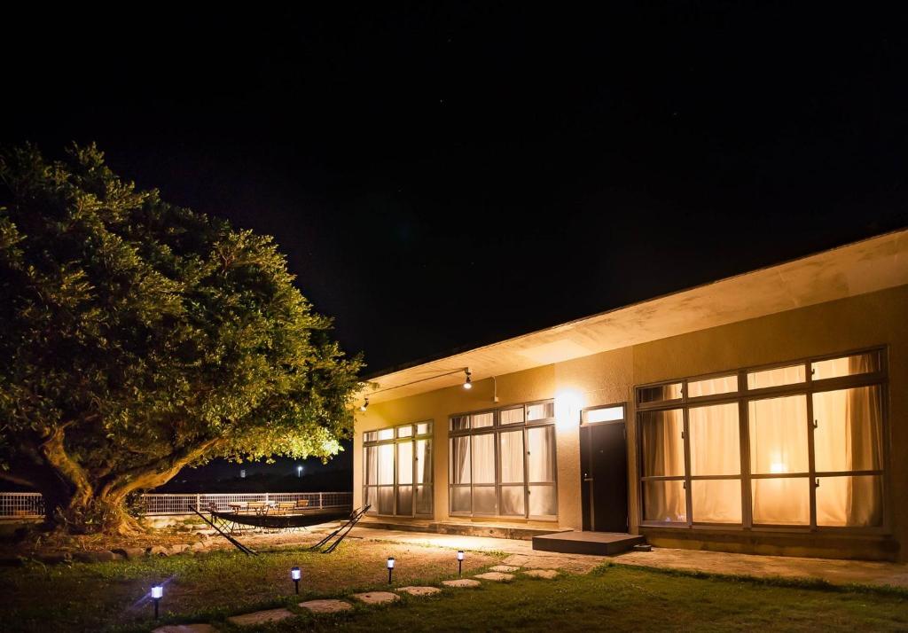 a building with windows and a tree at night at Gajumaru no niwa - Itoman - Vacation STAY 16759 in Itoman
