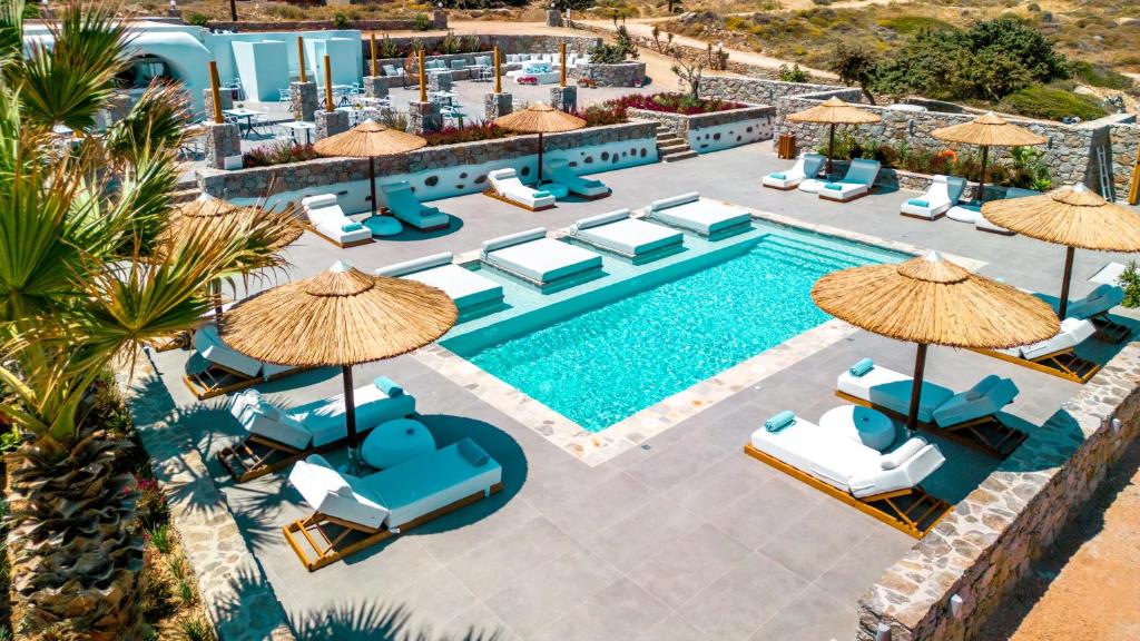 una imagen de una piscina en un hotel con sillas y sombrillas en Naxos Cave Suites en Stelida