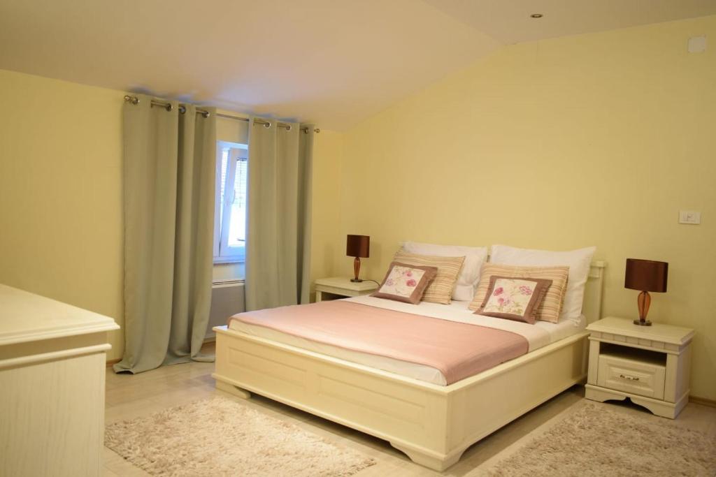 ein Schlafzimmer mit einem Bett mit zwei Nachttischen und einem Fenster in der Unterkunft Villa Šurmanci in Šurmanci