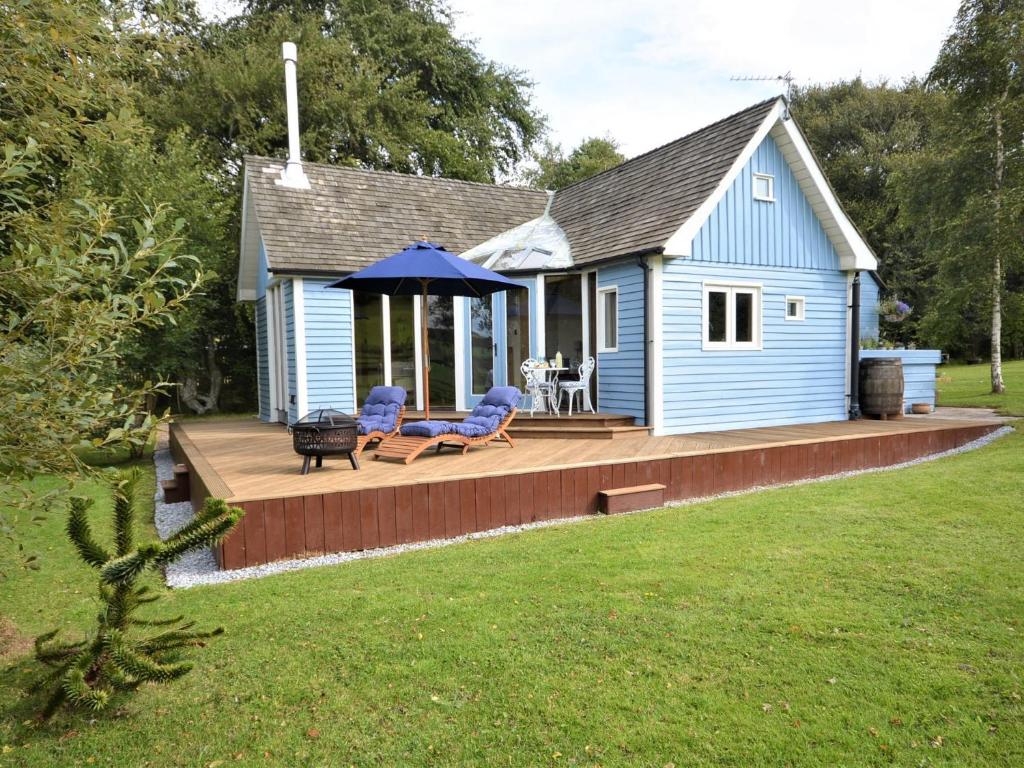 a blue house with a deck with two chairs at 1 Bed in Biggar 75414 in Biggar