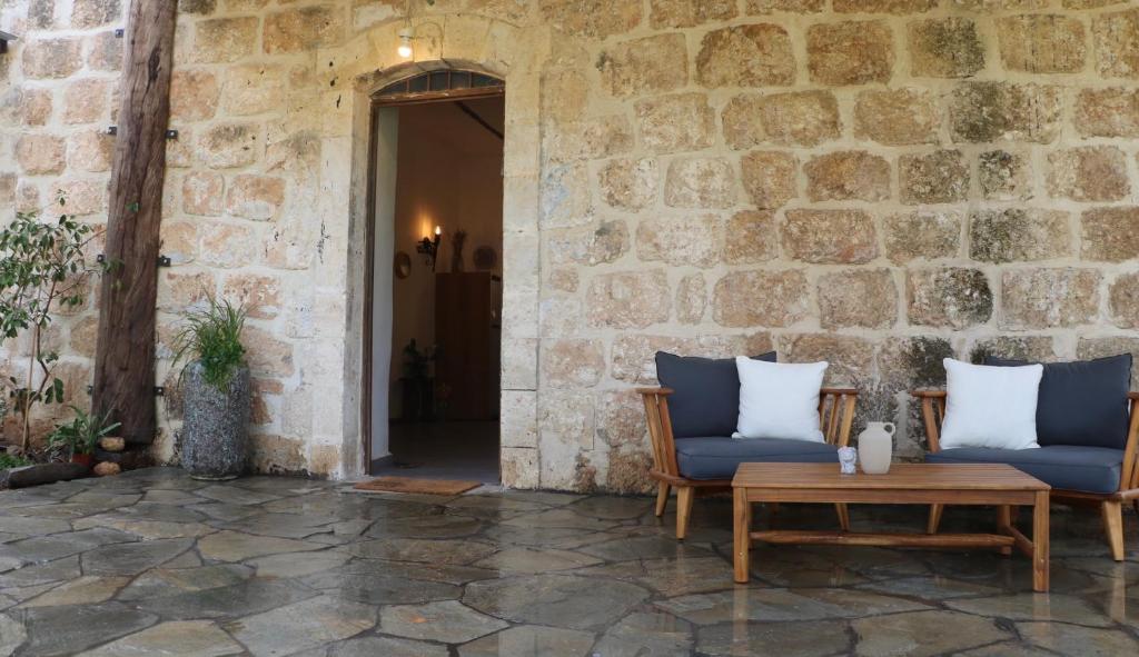 patio z 2 krzesłami, stołem i kamienną ścianą w obiekcie The stone house w mieście Kefar Daniyyel