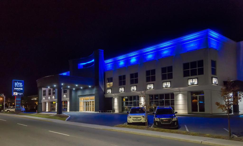 two cars parked in front of a building with blue lights at Hotel & Suites Le Dauphin Drummondville in Drummondville