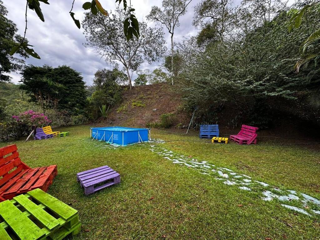 a group of colorful chairs sitting in the grass at Finca Bendita Caña in Villeta
