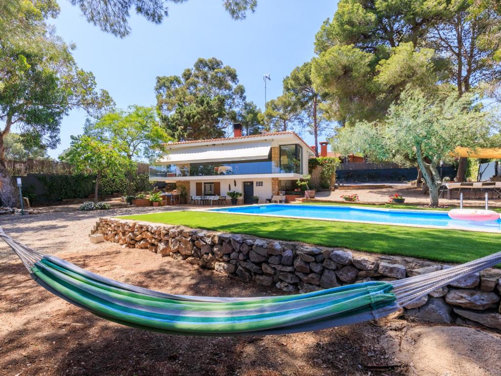a hammock in front of a house with a swimming pool at CHEZ ADELA in Almoster
