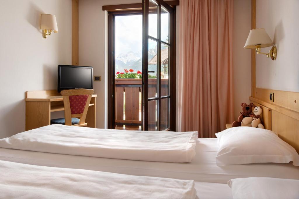 a bedroom with a large white bed with a desk and a window at Garni Aritz in Campitello di Fassa