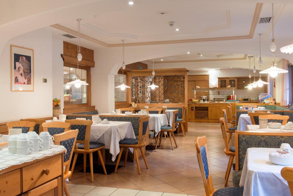 a restaurant with tables and chairs and a kitchen at Garni Aritz in Campitello di Fassa