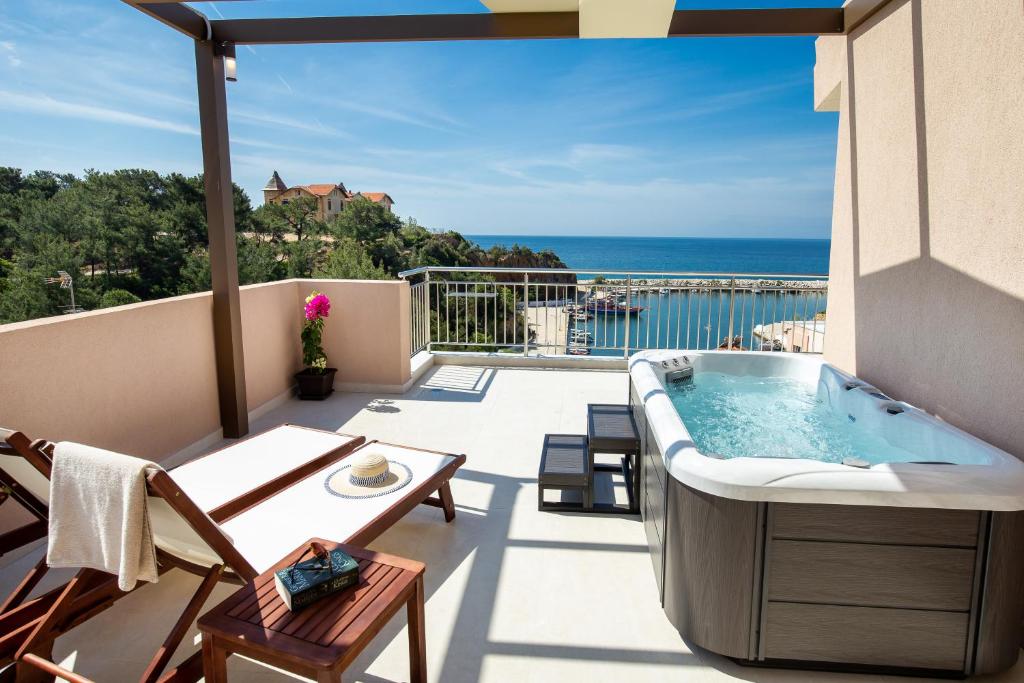 a hot tub on a balcony with a view of the ocean at Vela Bianca Suites in Limenaria