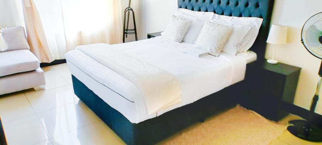 1 dormitorio con 1 cama con sábanas y almohadas blancas en Cedar Fourways Sandton en Trevallyn