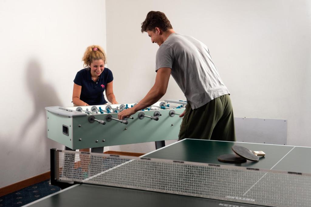 a man and a woman standing next to a ping pong table at Garni Aritz in Campitello di Fassa